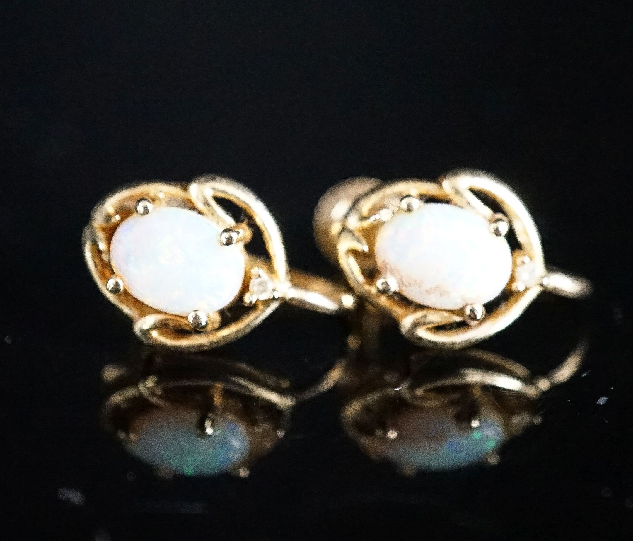 A modern pair of 585 yellow metal and oval white opal set ear clips, 12mm, gross weight 3.2 grams.